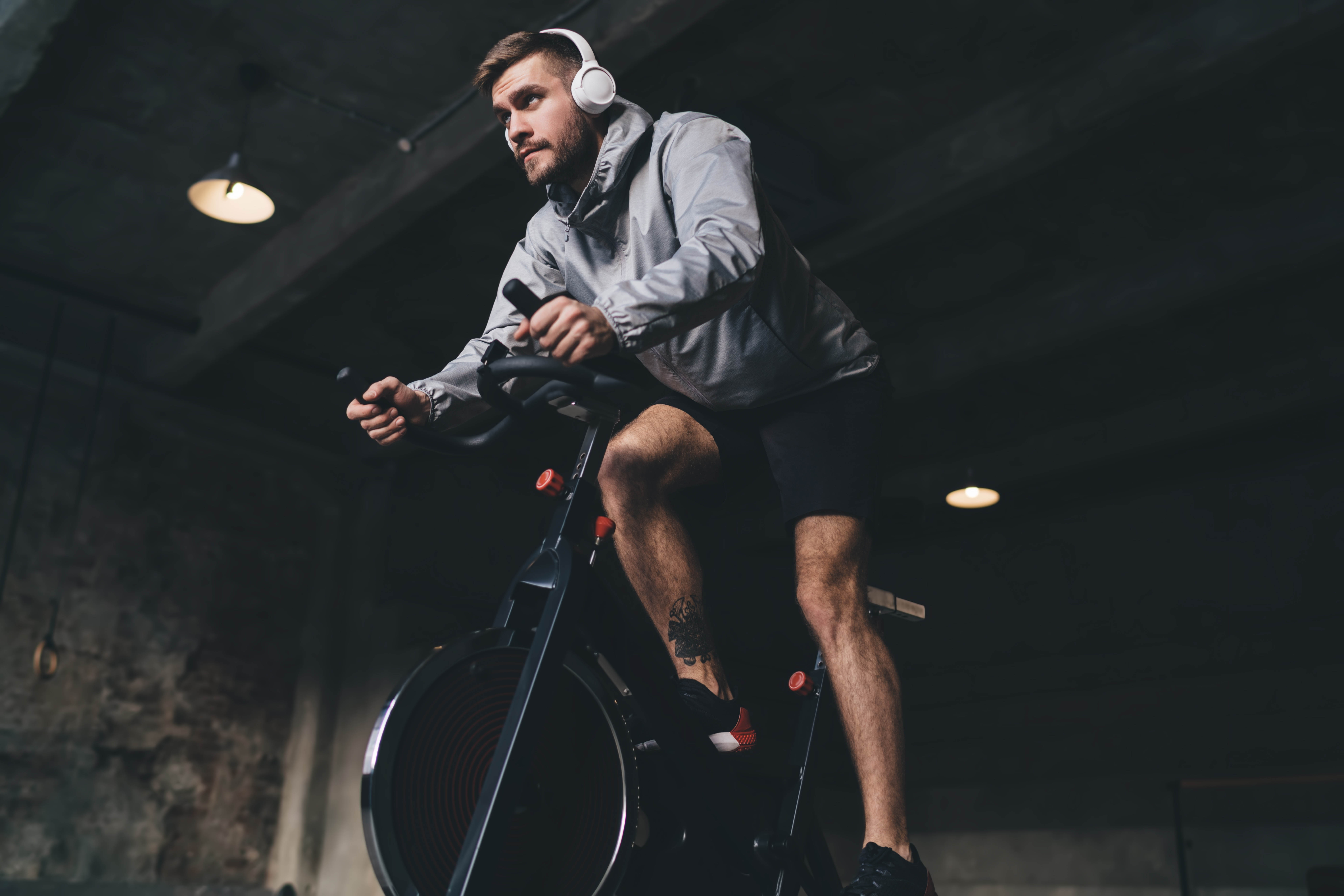 Man with headphones on, working out on a stationary bike in a gym Man with headphones on, working out on a stationary bike in a gym
